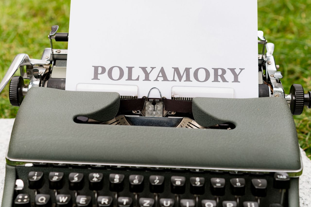 A vintage typewriter displaying the word Polyamory on paper outdoors, ideal for articles on relationships.
